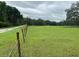 Grassy land with a fence alongside a paved road, presenting an opportunity for rural development or agricultural use at 17380 Sweetwater Rd, Dade City, FL 33523