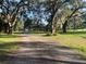 Long driveway leads to a charming yellow home with a white fence and sprawling green pastures at 17380 Sweetwater Rd, Dade City, FL 33523