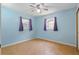 Comfortable bedroom with wood-look flooring, ceiling fan, and windows with light blue walls at 7214 Oakwood Dr, New Port Richey, FL 34652