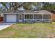 Charming home featuring a well-maintained lawn, a welcoming porch with decorative railing, and an attached garage at 7214 Oakwood Dr, New Port Richey, FL 34652