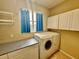 Functional laundry room with modern washer and dryer, storage cabinets, and a window with a view at 18018 Malakai Isle Dr, Tampa, FL 33647