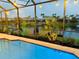 Screened in pool area overlooking the water with bistro lights and manicured landscaping at 18018 Malakai Isle Dr, Tampa, FL 33647