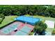 Aerial view of a sports complex with tennis and basketball courts and a blue roller hockey rink surrounded by lush greenery at 18018 Malakai Isle Dr, Tampa, FL 33647