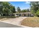 Single-story home with covered front parking, mature trees, and landscaping at 404 Courtney Dr, Temple Terrace, FL 33617