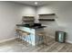Stylish bar area with black countertop, wooden stools, floating shelves, and light gray laminate wood flooring at 302 Coco Plum Ct, Oldsmar, FL 34677