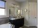 Modern bathroom featuring a large mirror above the vanity, a garden tub with grey tile, and neutral paint at 302 Coco Plum Ct, Oldsmar, FL 34677