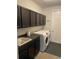 Functional laundry room featuring front load washer and dryer, sleek countertops, and built-in cabinets at 302 Coco Plum Ct, Oldsmar, FL 34677