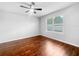 A bright bedroom with wood floors, a ceiling fan, and a window overlooking a green landscape at 10956 Carlton Fields Dr, Riverview, FL 33579