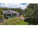 This aerial shot captures a lush backyard with a screened pool, palm trees, and stepping stones leading to the home at 1913 Blue River Rd, Holiday, FL 34691