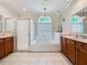 A spacious bathroom with a glass-enclosed shower, a soaking tub under a decorative window, and double vanity at 1913 Blue River Rd, Holiday, FL 34691
