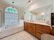 Bright bathroom featuring a soaking tub under a stained glass window and a vanity with wood cabinets at 1913 Blue River Rd, Holiday, FL 34691