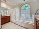 Well-lit bathroom with glass shower enclosure, soaking tub under a stained-glass window, and a wooden vanity at 1913 Blue River Rd, Holiday, FL 34691