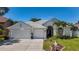 Well-maintained single-story home featuring a two-car garage, manicured lawn, and lush landscaping at 1913 Blue River Rd, Holiday, FL 34691
