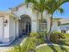 Close-up view of the front entrance with tropical landscaping and a screened-in porch and sitting area at 1913 Blue River Rd, Holiday, FL 34691