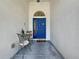 Charming front porch featuring a decorative blue door with sidelight, a small table, and two chairs at 1913 Blue River Rd, Holiday, FL 34691