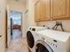 Efficient laundry area with washer and dryer, oak cabinets, and convenient access to other rooms at 1913 Blue River Rd, Holiday, FL 34691