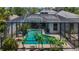 Enclosed pool area with a dark screen provides privacy and shade, with tropical plants surrounding the pool at 1913 Blue River Rd, Holiday, FL 34691