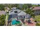 This aerial view features a screened-in pool, solar panels, and a well-maintained yard in a serene backyard setting at 1913 Blue River Rd, Holiday, FL 34691
