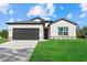 Beautiful new home with a dark garage door and well-manicured lawn under a bright blue cloudy sky at 1486 Ardisia St, North Port, FL 34288