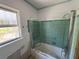 Bathroom with green tiles, window, and glass shower door in need of repair at 16107 Gulf Blvd, Redington Beach, FL 33708