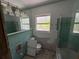 Bathroom with green tiles, window, and glass shower door, shows signs of damage at 16107 Gulf Blvd, Redington Beach, FL 33708