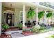 Close-up of a welcoming front porch featuring elegant columns, hanging ferns and lush landscaping, enhancing curb appeal at 2906 Country Breeze Dr, Plant City, FL 33567