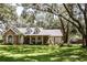 Inviting single-story home with stone detailing, dormer windows and a cozy front porch, framed by mature trees and lush green grass at 2906 Country Breeze Dr, Plant City, FL 33567