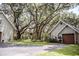 Detached garage nestled among mature trees with a rustic door. Well-maintained landscaping complements this garage at 2906 Country Breeze Dr, Plant City, FL 33567