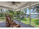 Relaxing screened porch with rocking chairs overlooking a lush yard and serene lake at 18620 Wayne Rd, Odessa, FL 33556