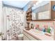 Retro bathroom featuring a floral shower curtain, unique shelving, and a pink tiled vanity and shower at 251 Tropic W Blvd, Largo, FL 33770