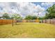 Large, grassy backyard featuring a wood fence, mature trees, and sunny skies at 1020 58Th N Ave, St Petersburg, FL 33703