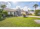 Well-maintained house with a lush green lawn, mature landscaping, and a paved driveway leading to the two-car garage at 2015 Gardenia Landings Ln, Sun City Center, FL 33573