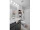Cozy bathroom with combination tub/shower, floating shelves, and vanity with grey cabinets offers efficient design at 12829 Kings Lake Dr, Gibsonton, FL 33534