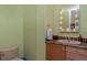Powder room with decorative mirror, stylish vanity, and soft green walls at 37511 Washington Loop Road, Punta Gorda, FL 33982