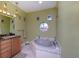 Bathroom with tub, vanity, and decorative circular window that peeks to the outside at 37511 Washington Loop Road, Punta Gorda, FL 33982