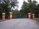 View of private entrance gate to property with orange columns and metal gate with decorative birds and flowers at 37511 Washington Loop Road, Punta Gorda, FL 33982