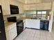 Cozy kitchen featuring white cabinets, black appliances and tile flooring at 115 1St E St # 103, Tierra Verde, FL 33715