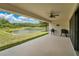 Large covered porch with ceiling fan and grill overlooks a scenic lake and backyard at 12784 Burns Dr, Odessa, FL 33556