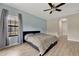Cozy bedroom with a large window, blue accent wall, ceiling fan, and wood-look tile flooring at 12784 Burns Dr, Odessa, FL 33556