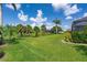 A lush backyard with palm trees, green grass, a screened-in patio, and well-maintained landscaping at 1751 Bobcat Trl, North Port, FL 34288