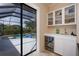 Convenient wet bar area with a wine cooler, a sink, glass shelving, and access to the outdoor pool area at 1751 Bobcat Trl, North Port, FL 34288