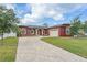 Elegant red home featuring a paver driveway, lush lawn, arched windows, and an attached two-car garage at 3244 55Th Ave N, St Petersburg, FL 33714