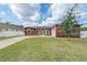 Stunning red home showcasing a lush lawn, arched windows, and a paver driveway leading to an attached garage at 3244 55Th Ave N, St Petersburg, FL 33714