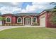 Elegant red home with arched windows, a paver pathway, lush lawn, and an attached two-car garage at 3244 55Th Ave N, St Petersburg, FL 33714