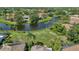 Wide aerial of homes near a dark pond amid lush greenery and trees on a sunny day at 6504 Virginia Xing, University Park, FL 34201