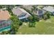 Aerial view of a backyard with a screened in porch, a large green lawn, and green trees at 6504 Virginia Xing, University Park, FL 34201