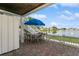 This patio with a view features a blue umbrella, dining table and chairs, overlooking a serene lake at 265 Seahorse Se Dr # B, St Petersburg, FL 33705
