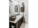 Bathroom vanity featuring dark cabinets, granite countertop, decorative mirror, and accent lighting at 9221 Mountain Magnolia Dr, Riverview, FL 33578
