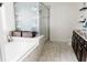 Bright bathroom with a soaking tub, glass shower, and dark wood vanity at 9221 Mountain Magnolia Dr, Riverview, FL 33578