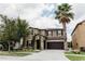 A two-story tan home with a well-manicured green lawn, tall trees, and an attached two-car garage at 9221 Mountain Magnolia Dr, Riverview, FL 33578